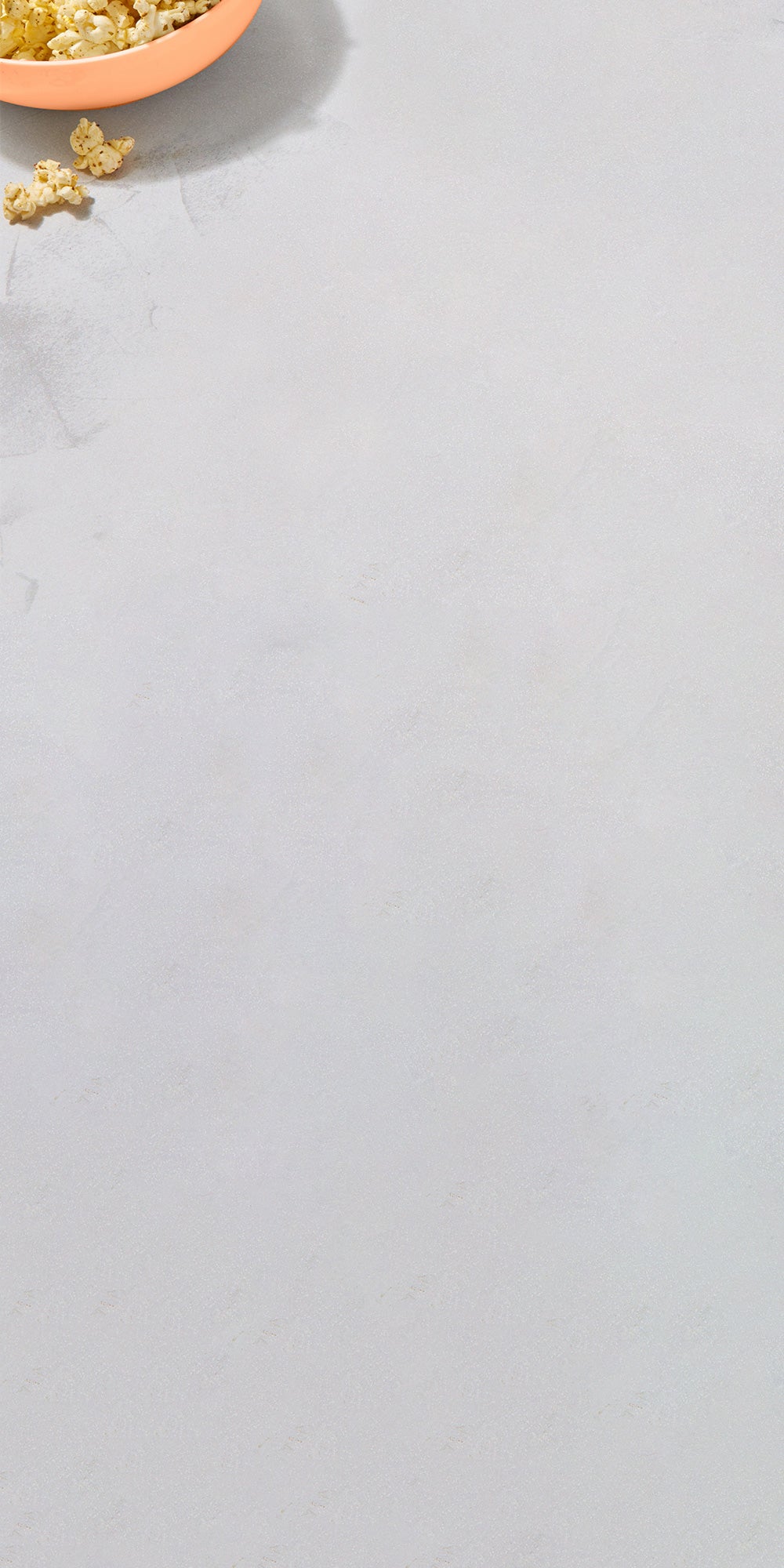 Bowl of popcorn on marble surface.