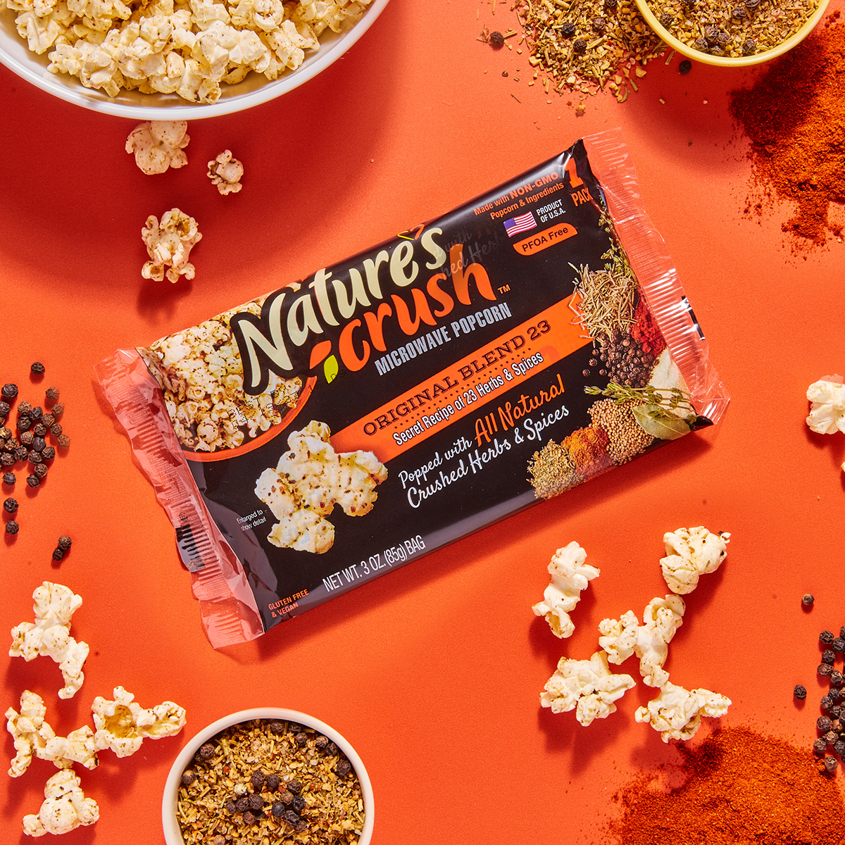 Bag of Original Blend 23 Popcorn surrounded by scattered popcorn, bowl of popcorn and spices..