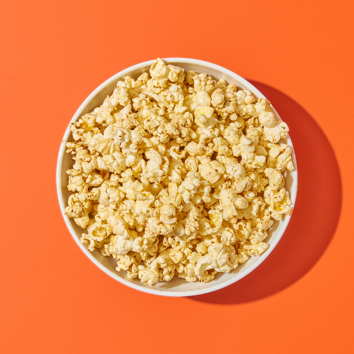 Bowl of Original Blend 23 Popcorn on red surface.