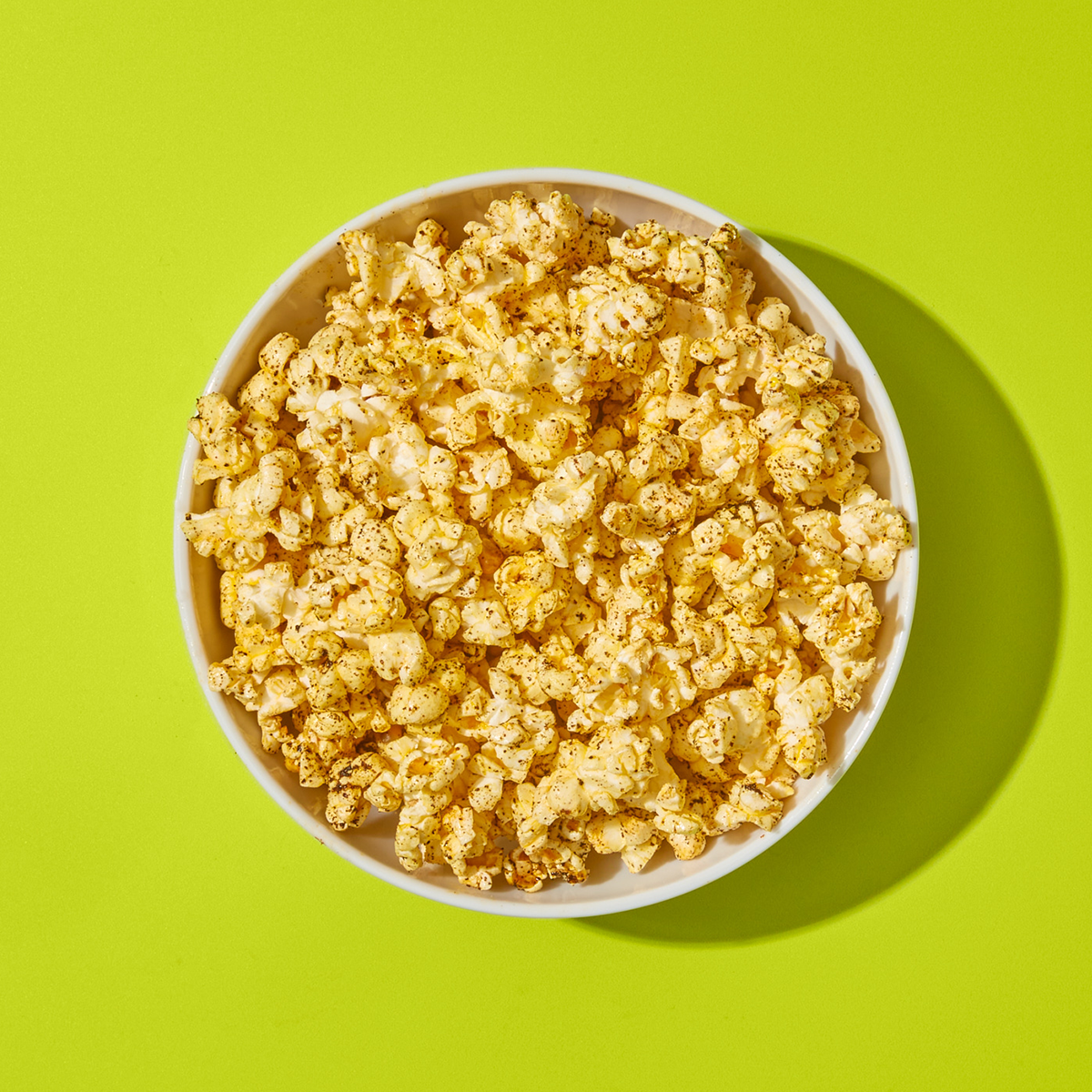 Bowl of Tex-Mex popcorn on green surface.